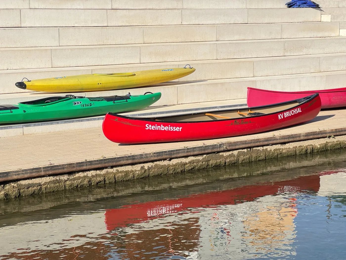 Kanus und Kajaks liegen an einer Treppe am Wasser bereit.
