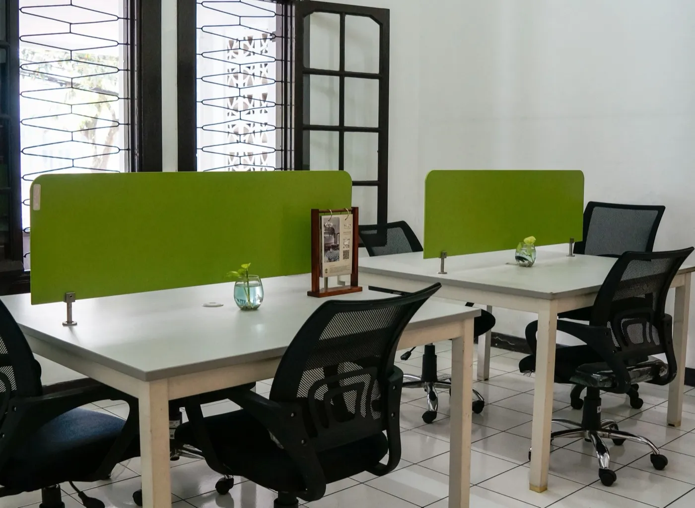 Coworking-Raum mit Schreibtischen, grünen Trennwänden und Bürostühlen.