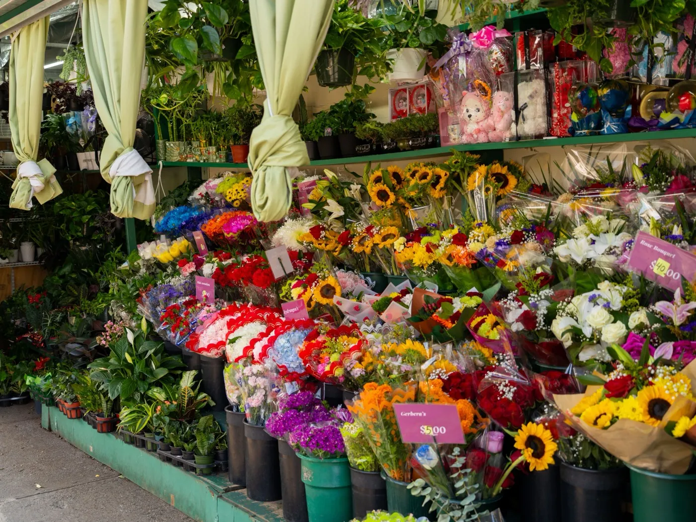 La devanture d’un fleuriste avec des bouquets colorés, des tournesols et des plantes vertes.
