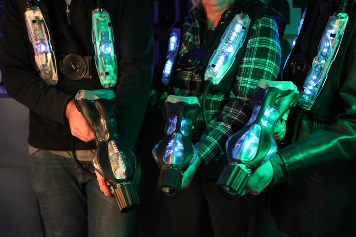 Spieler halten leuchtende Lasertag-Westen und Marker in der Hand.