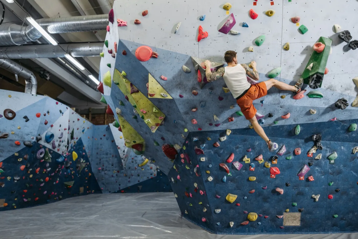 Kletterer an einer bunt bespickten Boulderwand in der Halle.