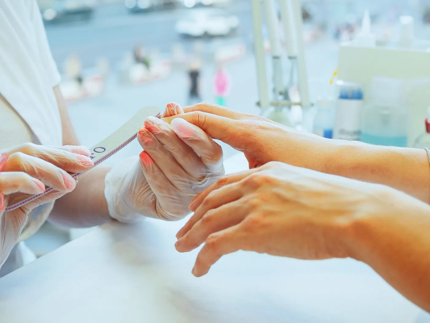 Une prothésiste ongulaire lime les ongles d’une cliente à la table de l’onglerie.