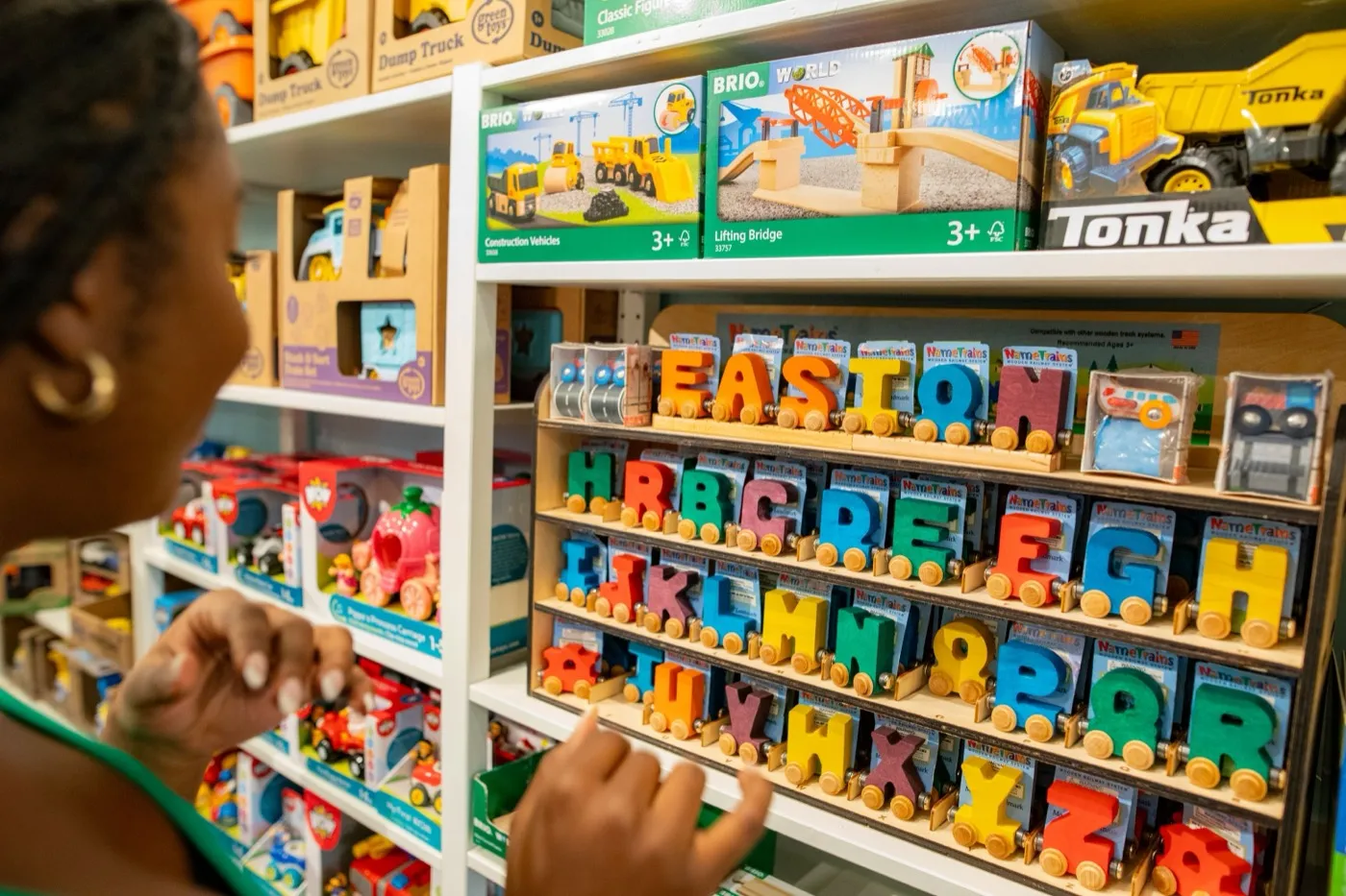 Kundin greift im Spielwarenladen nach bunten Holzbuchstaben im Regal.