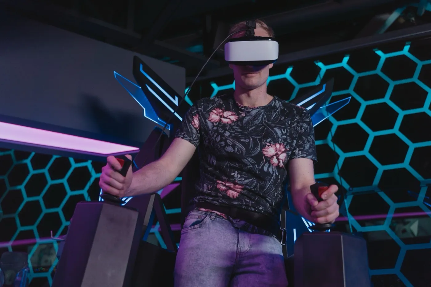 Spieler mit VR-Brille und Controllern vor einer blau beleuchteten Wabenwand.